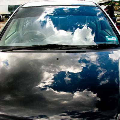 shiny sedan hood reflecting clouds